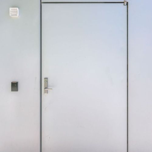 White fire-rated personnel door installed in industrial wall panel system
